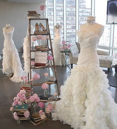 wedding gowns are displayed on display in a room with high ceilings and large windows