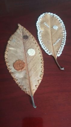 two decorative leaf shaped objects sitting on top of a wooden table next to each other