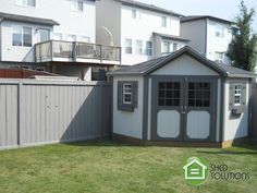 a backyard with a shed and fence in front of some apartment buildings that have balconies on the roof