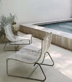 two white chairs sitting next to a swimming pool