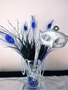 a vase filled with blue feathers and a mask