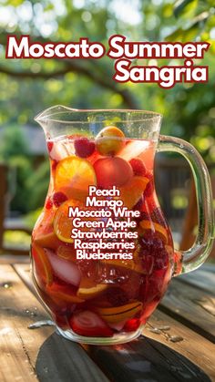 a pitcher filled with fruit sitting on top of a wooden table