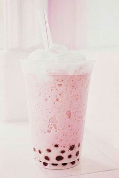 a pink drink with black spots and a straw in it