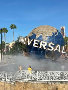 people are standing in front of the universal studios sign with steam coming out of it