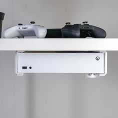 two video game controllers sitting on top of a shelf