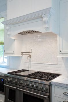 a stove top oven sitting inside of a kitchen next to white cabinets and counter tops