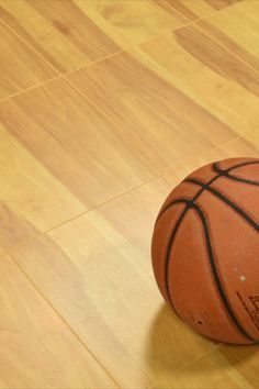 a basketball sitting on top of a hard wood floor next to a white and black ball