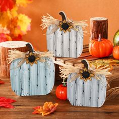 three wooden pumpkins decorated with sunflowers and burlocks on a table