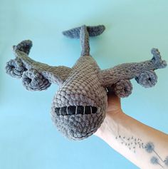 a hand holding up a knitted toy that looks like an airplane with its nose open