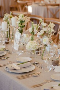 the table is set with white flowers and silverware