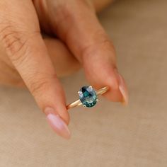 a woman's hand holding a ring with a blue stone