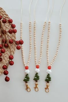 three beaded necklaces with christmas trees on them next to a basket and berries