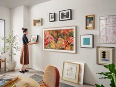 a woman standing in front of a wall with pictures on it and holding a clipboard