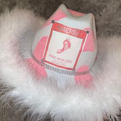 a pink moscato hat with white feathers around it's neck and label