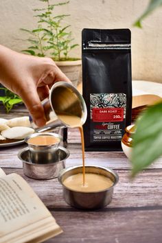 coffee being poured into small bowls on top of a table next to an open book