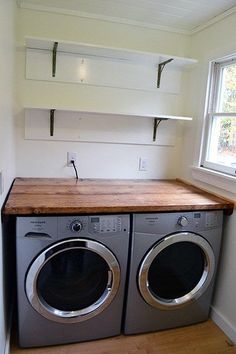 a washer and dryer in a small room with white cupboards on the wall