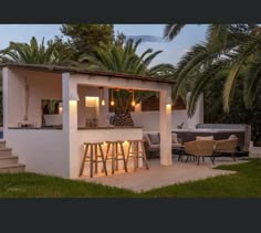 an outdoor bar is lit up at night with candles on the counter and palm trees in the background