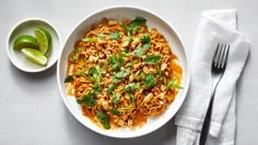 a white bowl filled with noodles and garnished with cilantro