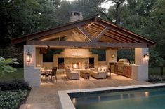 an outdoor living area next to a swimming pool and covered patio with fireplace, dining table and couches