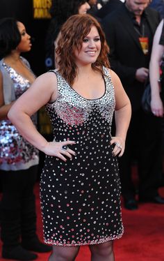 a woman in black and white dress standing on red carpet with her hands on her hips