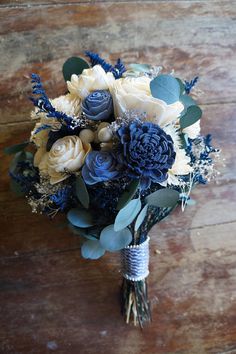 a bridal bouquet with blue and white flowers on a wooden surface, ready to be used as a bride's bouquet