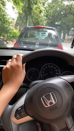 a person driving a car with their hand on the steering wheel