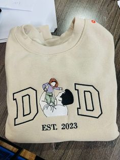 Looking for the perfect personalized gift for Father's Day or a special occasion? Our custom embroidered picture sweatshirts are a heartfelt choice. Featuring a beautifully detailed portrait outline and kids' names on the sleeve, these Dad Est Sweatshirts make for a unique and memorable gift. Whether it's for a dad-to-be, a proud father, or a loving husband, our embroidered t-shirts and sweatshirts are designed to celebrate family. Each piece is custom embroidered with care, making it a timeless keepsake that will be cherished for years to come. 🌸HOW TO ORDER: Please check our size and color charts to get exactly what you want. Select the correct size and color and fill out the personalization box 🌸ABOUT OUR SWEATSHIRTS/HOODIES: 35% Cotton, 65% Polyester Machine cold wash, inside out, wi Cricut Gifts For Parents, Things To Get Your Dad For Christmas, Gifts For Papa, Gifts For Dad Birthday, Dad Christmas Gifts, Christmas Presents For Dad, Wedding Sweatshirts, Gifts For Dads, Mrs Sweatshirt