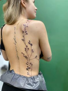 the back of a woman's body with tattoos on her upper and lower back