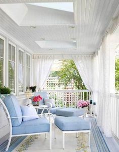 a white porch with blue furniture and curtains