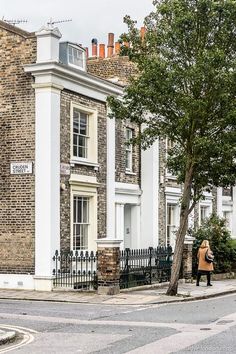 a woman standing on the sidewalk in front of a building