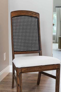 a wooden chair with a white cushion on top of it's seat and back