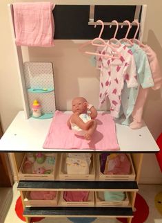 a baby sitting on top of a pink blanket next to a shelf filled with clothes