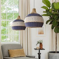 two blue and white lamps hanging from the ceiling above a couch in a living room