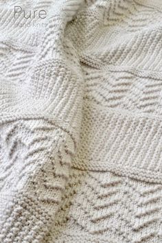 a white knitted blanket laying on top of a bed