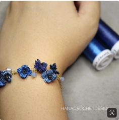 a woman's arm with blue flowers on it and two crocheted bracelets