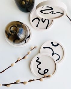 three plates with numbers on them sitting next to a vase and some branches in front of it