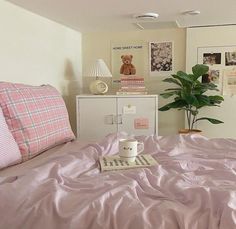 a bed with pink sheets and pillows in a bedroom next to a white cabinet filled with pictures