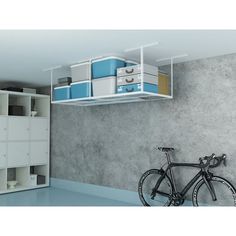 a bike is parked in front of a gray wall with shelves and shelving units