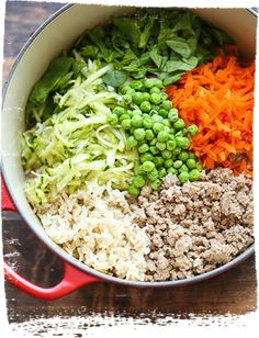 a pot filled with rice and vegetables on top of a wooden table