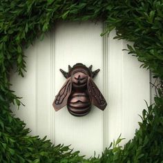 a close up of a door with a bee on it's face surrounded by green leaves