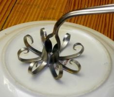 a white plate topped with metal utensils sitting on top of a wooden table