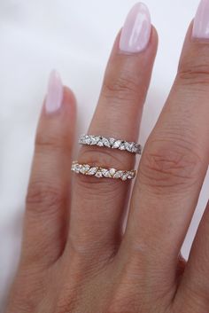 a woman's hand with two wedding bands on her fingers and one ring in the middle