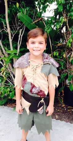 a young boy dressed up as peter panto from the movie peter panto, standing in front of some trees