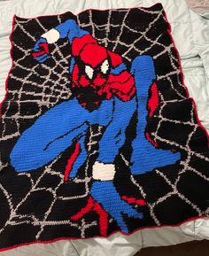 a crocheted spiderman blanket laying on top of a bed