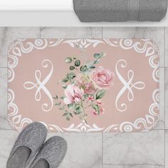 a pair of gray slippers sitting on top of a bathroom floor next to a pink rug