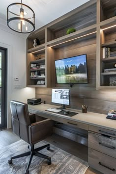 a home office with built - in shelving, desk and computer monitor on the wall