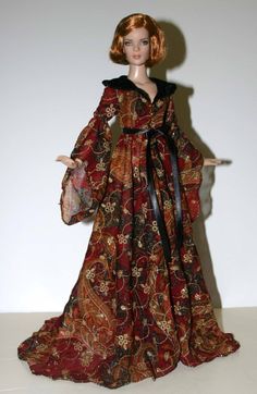 a doll wearing a red and black dress with a large shawl on it's head