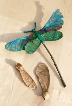 a blue dragonfly sitting on top of a wooden table next to a piece of wood