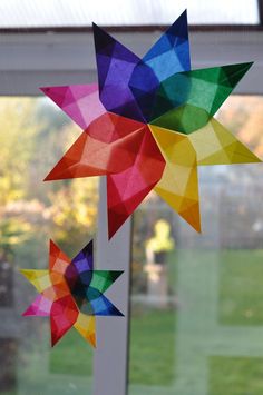 colorful paper stars hanging from the side of a window