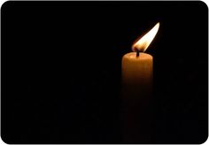 a lit candle in the dark with its light on